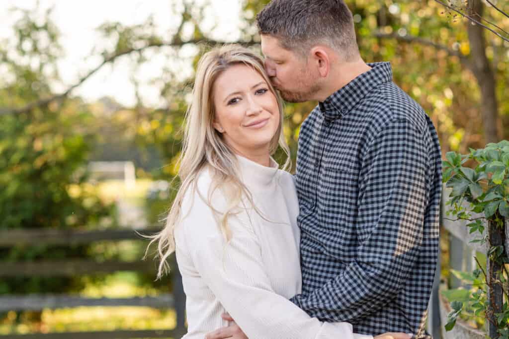 Couple in embrace next to rustic fence